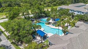A residential area with a swimming pool surrounded by palm trees and a blue-roofed building. - Modern 2BR 2BA Pool Gym Near Airport 8 (Tampa)