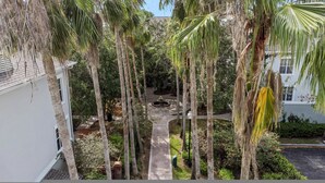 A courtyard with tall palm trees, a central fountain, and a brick pathway. - Modern 2BR 2BA Pool Gym Near Airport 8 (Tampa)