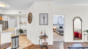 Un appartement moderne comprenant une cuisine, un coin repas et un salon. On peut admirer la Tour Eiffel depuis une fenêtre.