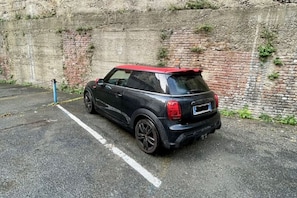 A black car parked in a lot with a brick wall and a blue pole. - The apartment welcomes guests into a warm, colorful, and personality-filled environment, designed to offer maximum livability and relaxation during your stay.The living area is the heart of the home: a large, bright living room where guests can gather to (Torino)