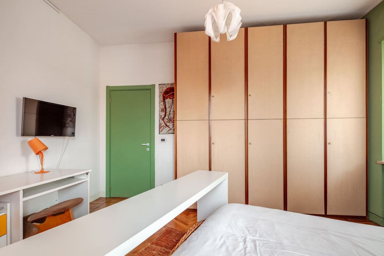 Un dormitorio con cama, escritorio, televisión y armario.
