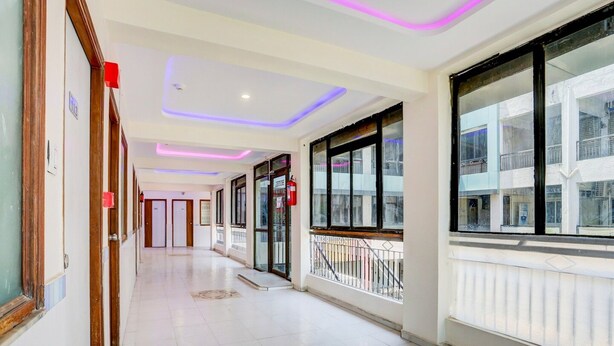 A corridor with tiled flooring, wooden doors, and large windows with balconies. - Super Collection O Ahmedabad Airport (Ahmedabad)
