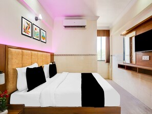 A hotel room with a bed, air conditioning unit, TV, and artwork on the wall. - Super Collection O Ahmedabad Airport (Ahmedabad)