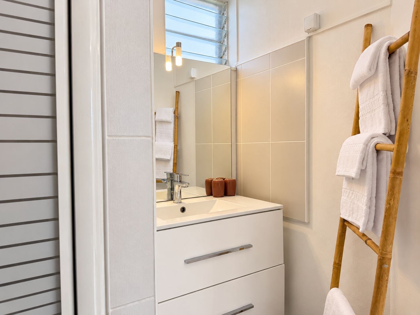 Un baño moderno con tocador blanco, espejo y perchero.