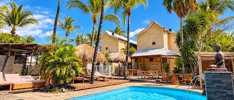 Une piscine entourée de palmiers et de chaises longues en bois.