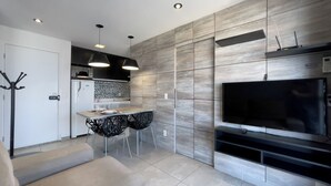 A modern kitchen with a dining area, a flat-screen TV, and a coat rack. - SP New Home (São Paulo)