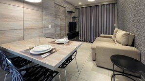 A modern living room with a dining area, including a table set for two, a sofa, and a TV. - SP New Home (São Paulo)