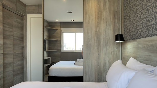 A hotel room with a bed, a wardrobe, a mirror, and a window. - SP New Home (São Paulo)