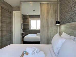 Ein Hotelzimmer mit Bett, Kleiderschrank, Spiegel und Fenster.