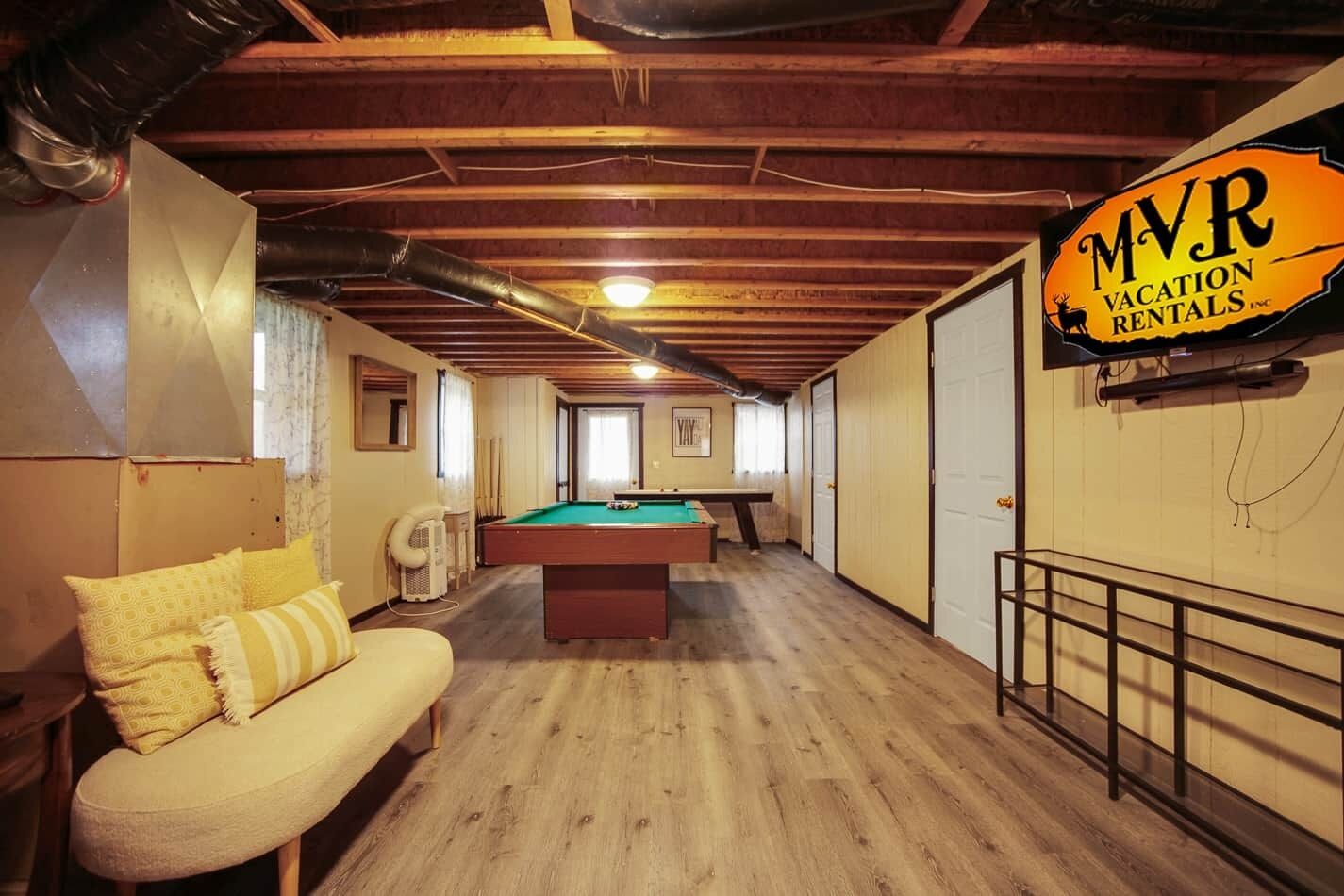 A room with a pool table, a sofa, and a sign for MVR Vacation Rentals Inc.