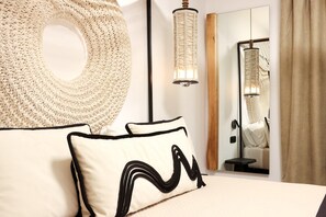 A bedroom with a large circular woven headboard, a bedside lamp, a mirror, and a bed with two pillows.
