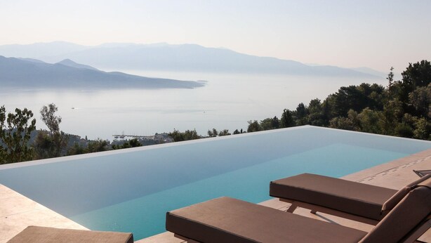 Ein Pool mit Liegestühlen und Bergblick im Hintergrund.