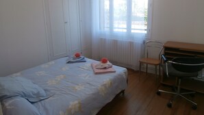A bedroom with a bed, a chair, a desk, and a window with curtains. - CHATOU CITY CENTER (Chatou)