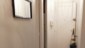 A hallway with two metal-framed chairs and a small table, a white door, and a light fixture. - CHATOU CITY CENTER (Chatou)