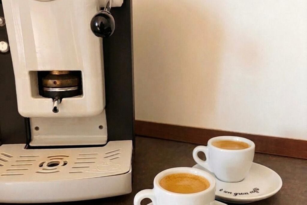 A coffee machine with two cups of coffee on a table.