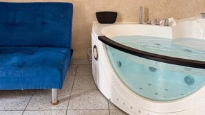 Ein Badezimmer mit einer Badewanne, einem blauen Sofa und einem gefliesten Boden.