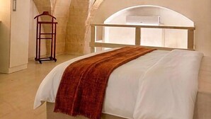 Ein Schlafzimmer mit einem Bett, einem Holzkleiderbügel und einem Fenster mit weißem Rahmen.