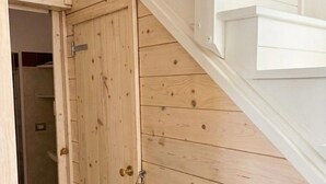 Eine Holztür mit Messingklinke, eine weiße Wand und eine Treppe.