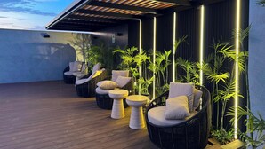 A rooftop patio with outdoor seating, vertical lighting, and bamboo plants. - Luxurious brand-new apartment just a few blocks from Larcomar (Miraflores)