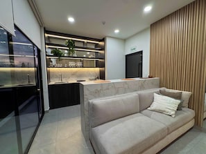 A modern kitchen with a marble countertop, a built-in sink, and a black refrigerator. - Luxurious brand-new apartment just a few blocks from Larcomar (Miraflores)