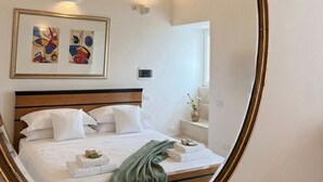 A neatly made bed with white linens, a green throw blanket, and a small vase on the nightstand. - Le Dimore - Suite Levante (Gallipoli)