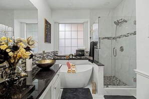Un baño moderno con una bañera grande, zona de ducha y ventana que proporciona luz natural.