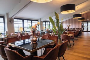 Un vaste espace dédié à la salle à manger, doté de hauts plafonds, de grandes fenêtres et de mobilier moderne.