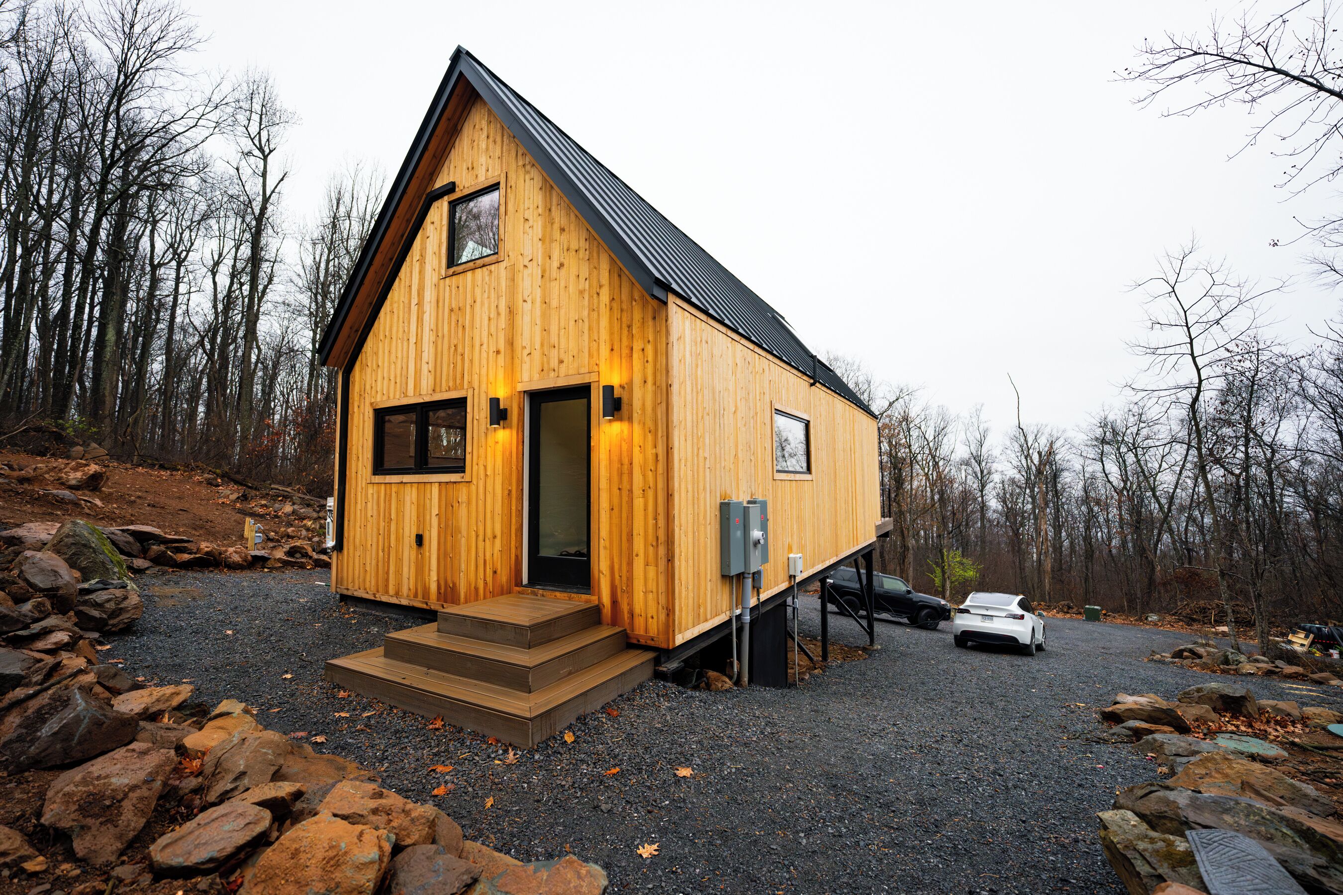 A wooden cabin with a sloped roof, a front door, and a small set of steps leading to the entrance.