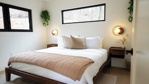A bedroom with a bed, two bedside tables, a window, and wall-mounted lighting. - Getaway Cabin Retreat in Shenandoah Valley - Hot Tub, Sauna, Cold Plunge (Shenandoah Farms)