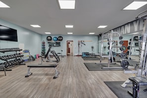 A gym with exercise equipment, a wall-mounted TV, and a mirror. - Studio w/ Gym & Pool Access (Pigeon)