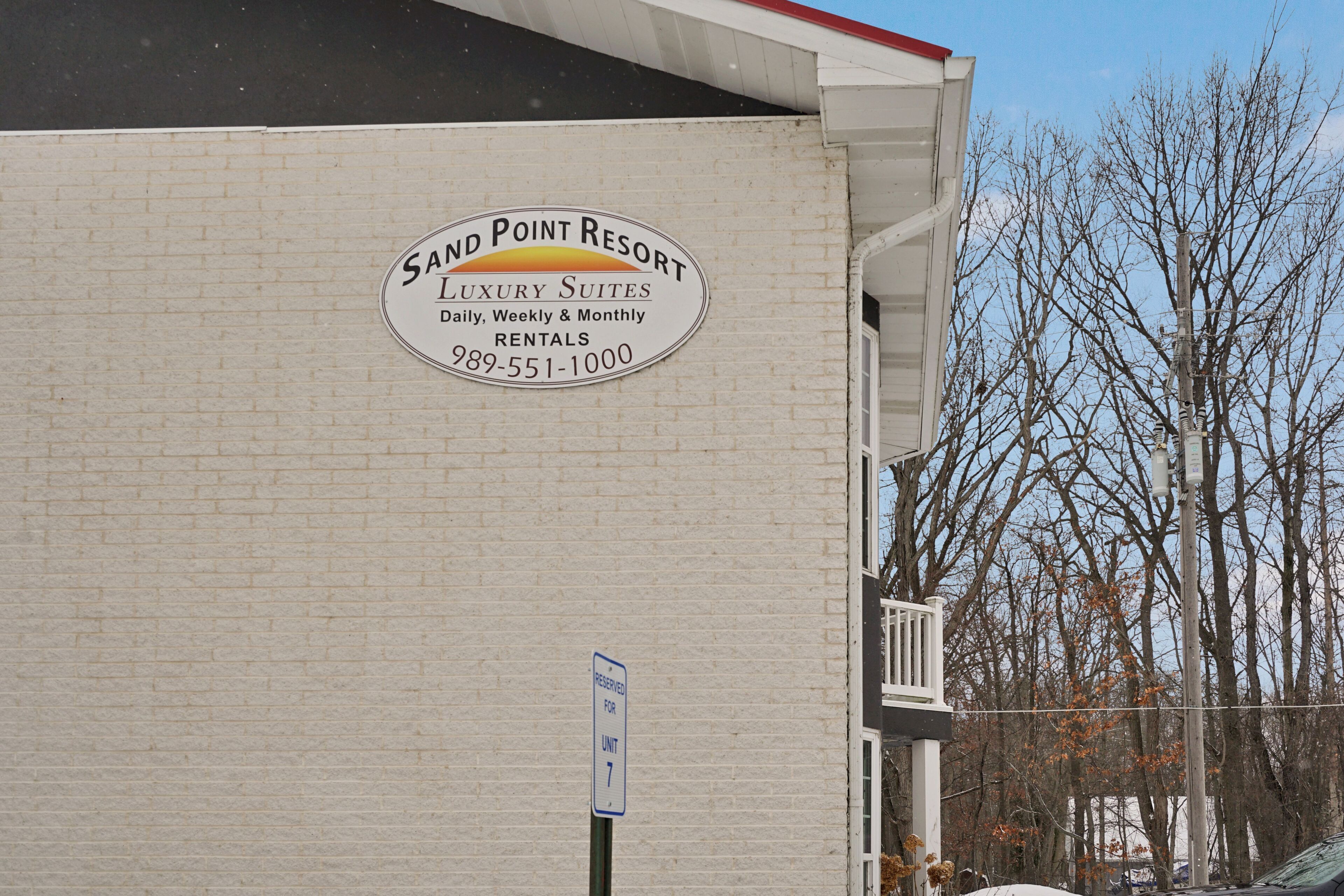 A building with a sign for Sand Point Resort, indicating it offers luxury suites with daily, weekly, and monthly rentals.