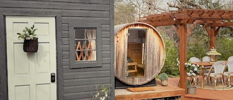 A rustic cabin with a door, a small window, and a wooden sauna structure.