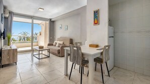 A modern living room with a dining area, a sofa, a coffee table, and a view of the outdoors. - Apartment 'Rosa De Los Vientos' with Sea View, Wi-Fi, and Air Conditioning (Calpe)