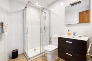 A modern bathroom with a glass-enclosed shower, a white toilet, a dark wooden vanity, and a mirror above the sink. - Apartment 'Rosa De Los Vientos' with Sea View, Wi-Fi, and Air Conditioning (Calpe)