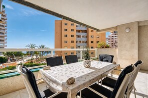 An outdoor dining area with a table set for four, chairs, a potted plant, and a view of a residential building. - Apartment 'Rosa De Los Vientos' with Sea View, Wi-Fi, and Air Conditioning (Calpe)