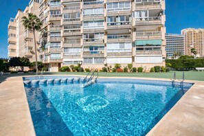 A swimming pool with steps, surrounded by a multi-story building with balconies and a clear sky. - Apartment 'Rosa De Los Vientos' with Sea View, Wi-Fi, and Air Conditioning (Calpe)