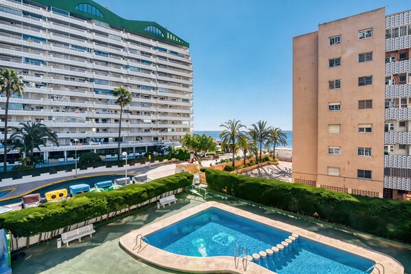 A hotel with a pool, palm trees, and a view of the sea. - Apartment 'Rosa De Los Vientos' with Sea View, Wi-Fi, and Air Conditioning (Calpe)