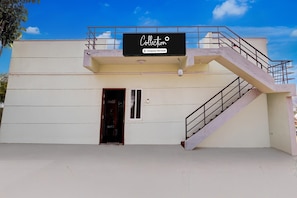 A building with a staircase, a Coca-Cola branded door, and a sign that reads 'Collection Company-Serviced.'