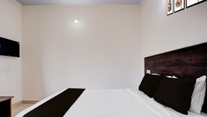 Un dormitorio con cama, televisor de pantalla plana en la pared y cabecero de madera.