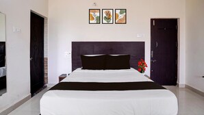 Une chambre d’hôtel avec un grand lit, une tête de lit sombre et trois œuvres d’art encadrées accrochées au mur.