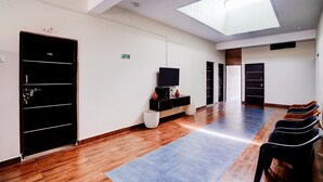 Un vestíbulo de hotel con tragaluces, una mesa de recepción, un televisor y una fila de sillas.