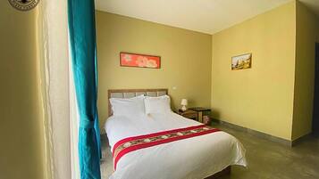 A hotel room with a bed, a nightstand, a lamp, and two framed pictures on the wall.