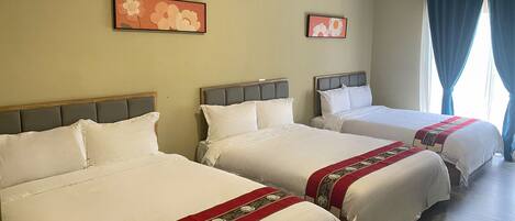 Habitación de hotel con tres camas, aire acondicionado de pared y dos cuadros florales.