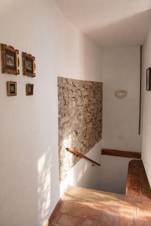 A hallway with a stone wall, a wooden bench, and framed pictures on the wall. - Panorama Lake Relax (Nesso)
