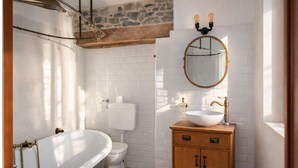 Een badkamer met een vrijstaand bad, een toilet, een houten wastafelmeubel met een wastafel en een spiegel erboven.