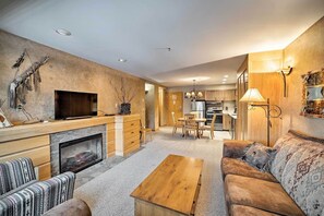 Living room featuring a fireplace, seating, and an adjacent dining area and kitchen. - Big Sky Mountain Retreat | Ski-In/Ski-Out (Big Sky)