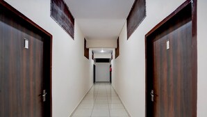 A hallway with two wooden doors, white walls, and a tiled floor.