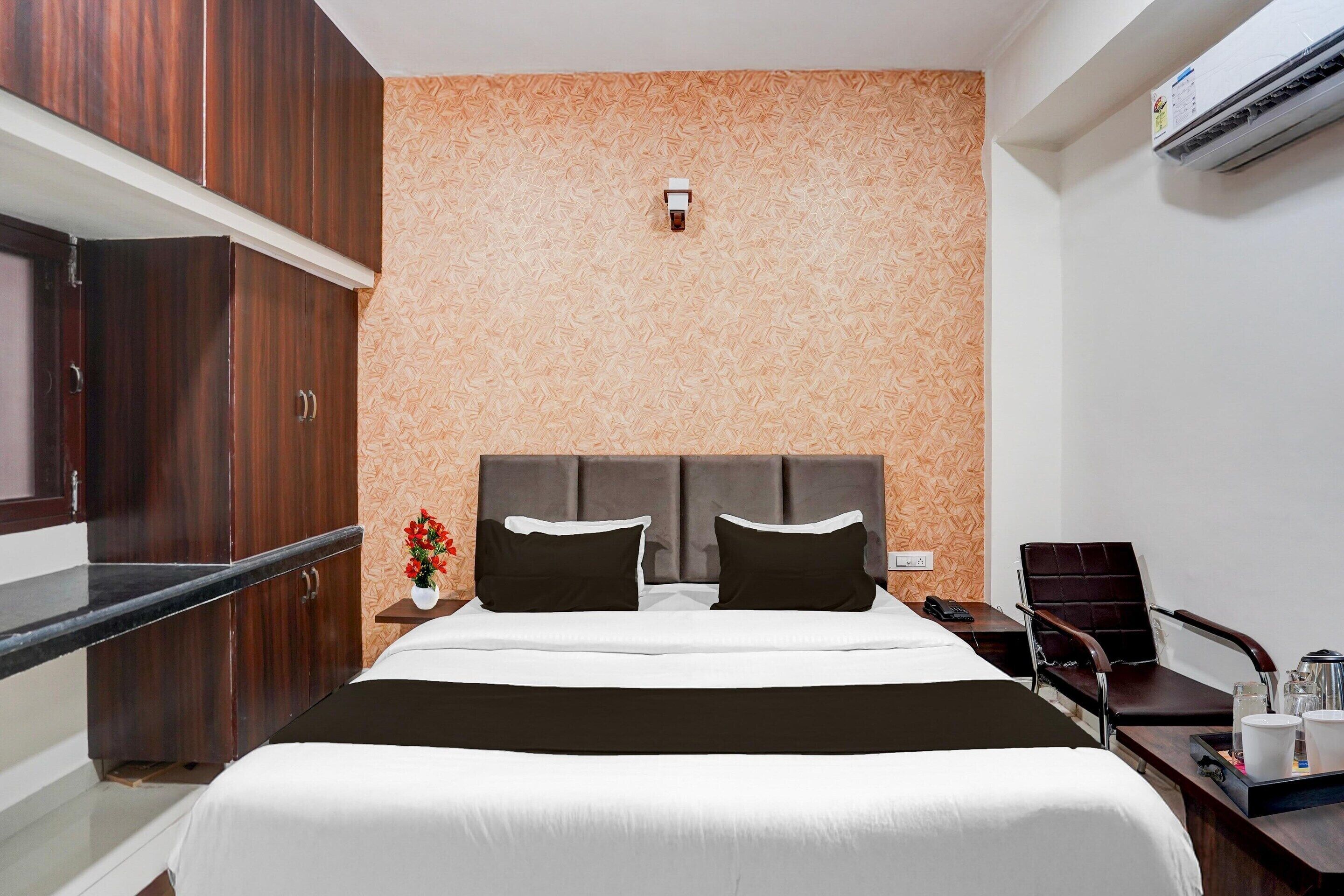 Ein Hotelzimmer mit Bett, Nachttisch, Schreibtisch, Stuhl und Klimaanlage.