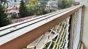 A balcony with a metal railing overlooking a residential area with houses and trees. - Beautiful 1-bedroom hotel with AC in peaceful Rishikesh (Rishikesh)