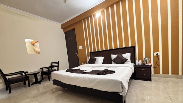A hotel room with a large bed, a desk, a chair, and a nightstand. - Beautiful 1-bedroom hotel with AC in peaceful Rishikesh (Rishikesh)